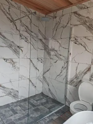 a bathroom with a toilet and a marble wall at Elias Nefale Eco Estate in Mitxetweni