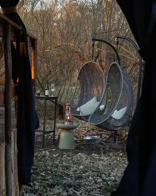 two wicker chairs and a table with a candle at Kruger Untamed - Satara Plains Camp in Die Brug