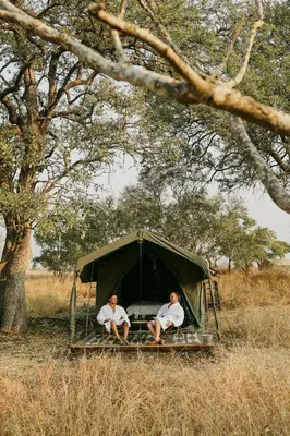 two men sitting in a tent under a tree at Kruger Untamed - Satara Plains Camp in Die Brug