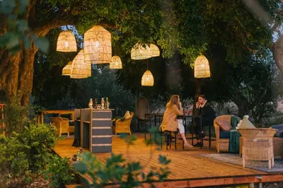 a man and woman sitting at a table under a tree at Kruger Untamed - Satara Plains Camp in Die Brug
