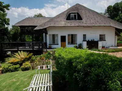 a house with a thatched roof and a bench in front at Boven Villa in Waterval Boven