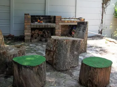 a fire pit with logs and green grass at Boven Villa in Waterval Boven