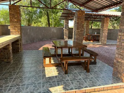 a patio with a wooden table and bench and a brick wall at Azalea Accommodation in Northam