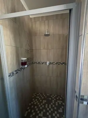 a bathroom with a shower with a checkerboard floor at Azalea Accommodation in Northam