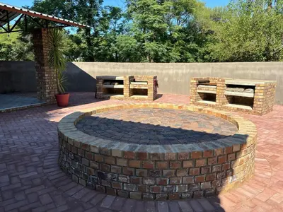 a brick fire pit with two benches on a patio at Azalea Accommodation in Northam