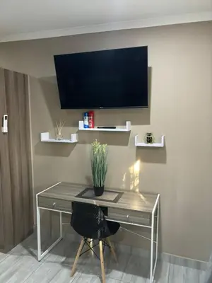 a room with a desk with a television on the wall at Azalea Accommodation in Northam