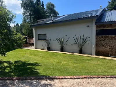 a white house with plants in a yard at Rest Guesthouse in Dullstroom