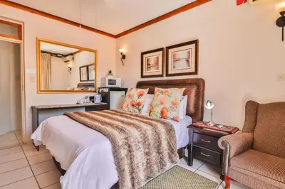 a bedroom with a bed and a couch and a chair at Cascade Villa Guesthouse in Secunda