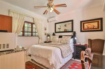 a bedroom with a bed and a ceiling fan at Cascade Villa Guesthouse in Secunda