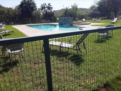 a fence with chairs around a swimming pool at Nikita Portuguese Restaurant and Motel in Lanseria