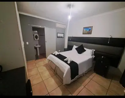 a bedroom with a large bed and a bathroom at Nikita Portuguese Restaurant and Motel in Lanseria