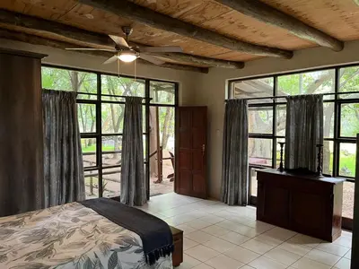 a bedroom with a bed and large windows at Blyde River Studio Units - bottom unit in Hoedspruit