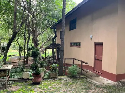 a building with a door and a table and trees at Blyde River Studio Units - bottom unit in Hoedspruit