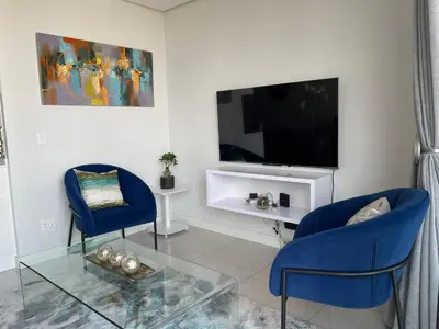 a living room with two blue chairs and a tv at Entire Apartment in Waterfall, South Africa in Midrand