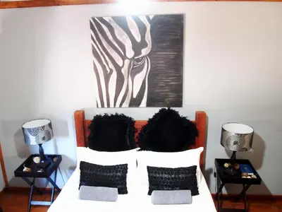 a bedroom with a bed with two lamps and a painting at Havana Nights in Graskop