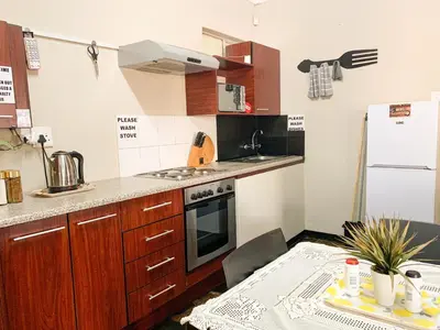 a kitchen with wooden cabinets and a table in front of a refrigerator at Havana Nights in Graskop
