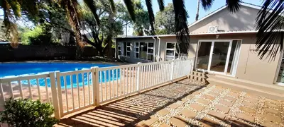 a house with a white fence next to a swimming pool at Joy Haven - Open Plan Studio in Centurion