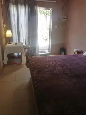 a bedroom with a bed and a window and a table at Walalawasala in Polokwane