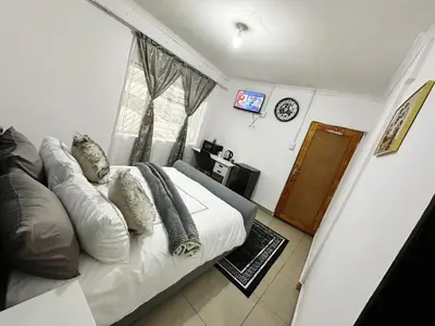 a bedroom with a bed with pillows and a window at Chilled Vibe Lodge in Soshanguve