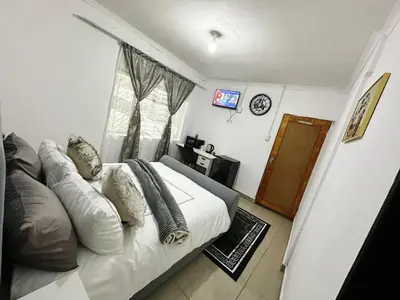 a bedroom with a bed with pillows and a window at Chilled Vibe Lodge in Soshanguve