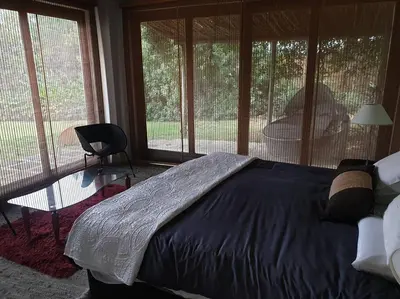 a bedroom with a bed and a table and windows at Glenferness AH Villa in Midrand