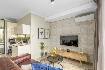 a living room with a couch and a tv on a wall at Mvilo, Luxury Apartment, Ellipse Waterfall in Midrand