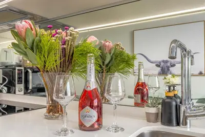 a kitchen counter with two wine glasses and flowers at Mvilo, Luxury Apartment, Ellipse Waterfall in Midrand