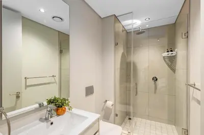 a white bathroom with a shower and a sink at Mvilo, Luxury Apartment, Ellipse Waterfall in Midrand