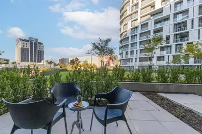 a patio with chairs and a table and a building at Mvilo, Luxury Apartment, Ellipse Waterfall in Midrand