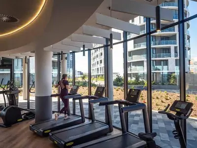a woman is running on treadles in a gym at Mvilo, Luxury Apartment, Ellipse Waterfall in Midrand