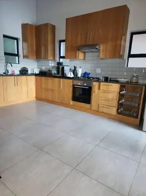 a large kitchen with wooden cabinets and a tile floor at BondMakers at Kosmos in Hartbeespoort