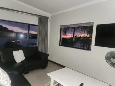 a living room with a black couch and a window at BondMakers at Kosmos in Hartbeespoort