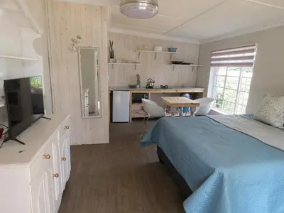 a bedroom with a blue bed and a kitchen at Avalon Cottages in Barberton