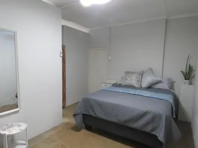 a bedroom with a bed in a white room at Avalon Cottages in Barberton