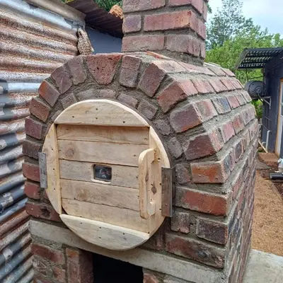 a brick oven with a door in a brick wall at Avalon Cottages in Barberton