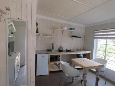 a kitchen with a table and chairs in a room at Avalon Cottages in Barberton