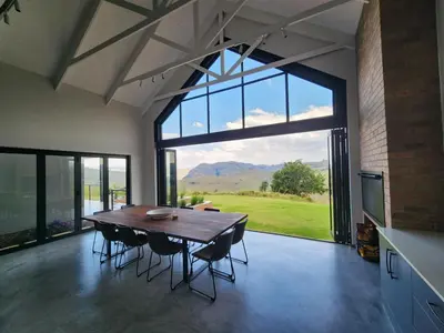 a dining room with a table and chairs and a large window at Bald Ibis (856 Highland Gate) in Dullstroom