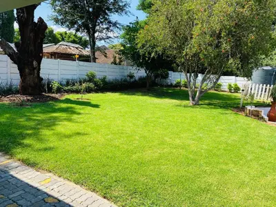 a yard with a tree and a white fence at Cozy Guest Suite 2-with back up power in Midrand