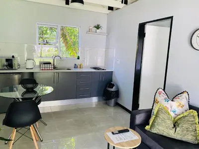 a living room with a table and a kitchen at Cozy Guest Suite 2-with back up power in Midrand