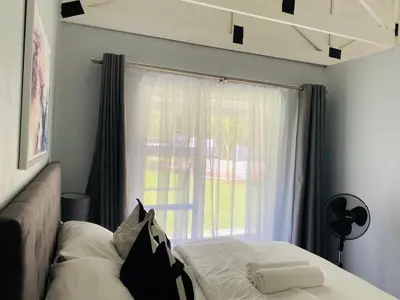 a bedroom with a bed and a large window at Cozy Guest Suite 2-with back up power in Midrand