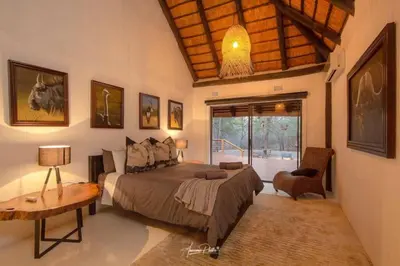 a bedroom with a bed and a wooden ceiling at Luxury GuesthouseCo Butterfly House in Marloth Park