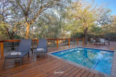 a deck with a swimming pool on a wooden deck at Luxury GuesthouseCo Butterfly House in Marloth Park