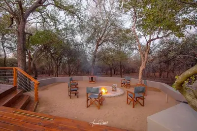 a patio with chairs and a firepit with a table and chairs at Luxury GuesthouseCo Butterfly House in Marloth Park