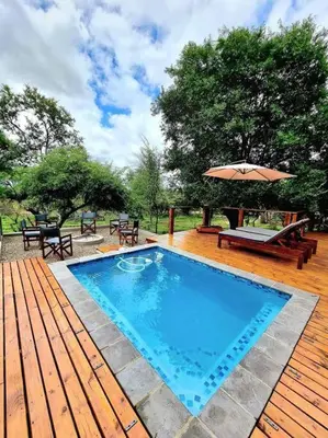 a swimming pool on a wooden deck with an umbrella at Luxury GuesthouseCo RiverDance in Marloth Park