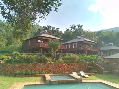 a group of houses with a swimming pool in a yard at Faith Cabin in Waterval-Onder