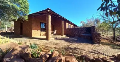 a brick house with a stone wall at Pumula Game Farm in Eersbewoond