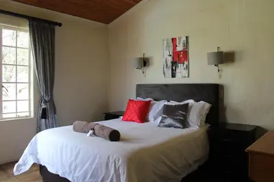a bedroom with a large white bed with red pillows at Pumula Game Farm in Eersbewoond