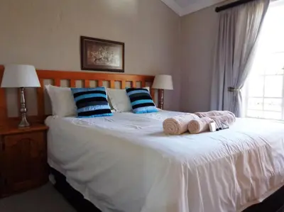 a bedroom with a white bed with pillows and a window at Pumula Game Farm in Eersbewoond
