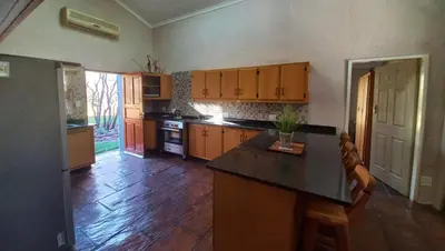 a kitchen with wooden cabinets and a black counter top at Pumula Game Farm in Eersbewoond