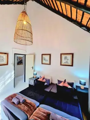 a living room with a couch and a chandelier at Luxury GuesthouseCo HiddenHouse in Marloth Park